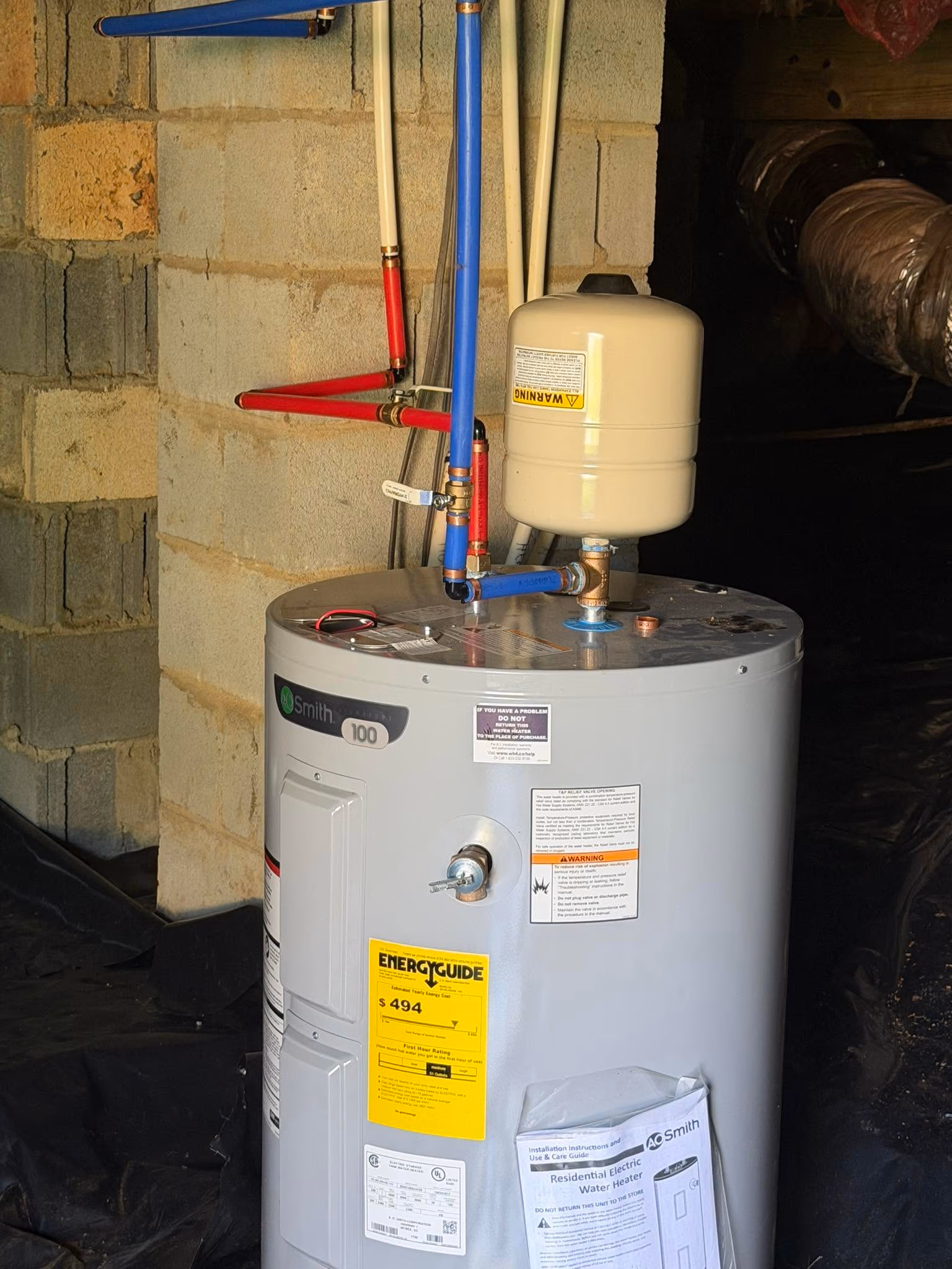AO Smith residential electric water heater with connected red and blue pipes and energy guide label.
